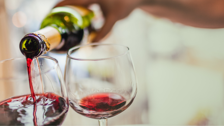En vinflaska serverar i två glas.